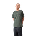 Carhartt WIP S/S Pocket T-Shirt en color verde velvet, vista frontal sobre modelo masculino. Camiseta de manga corta con cuello redondo, bolsillo en el pecho con etiqueta cuadrada tejida Carhartt WIP y corte regular fit. Combinada con vaqueros oscuros cargo y cadena plateada.