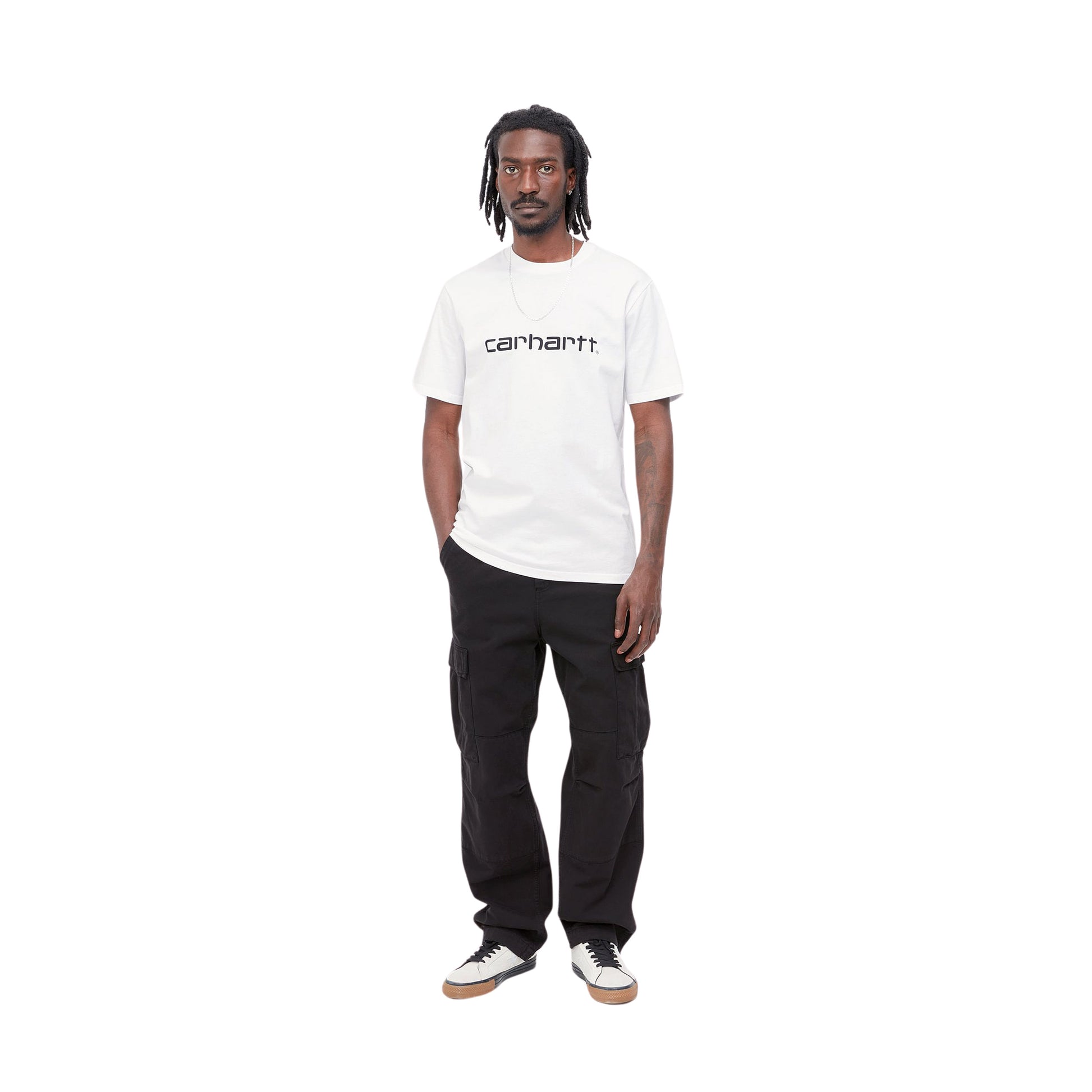 Hombre con la camiseta básica de manga corta Carhartt WIP S/S Script T-Shirt Blanca con el logo Carhartt en Negro y pantalón negro