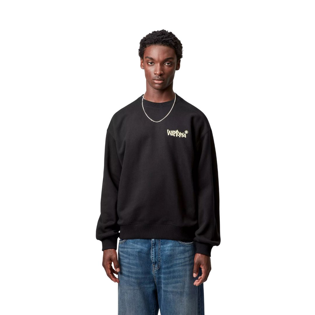 Carhartt WIP Wiptopia Sweatshirt color Black en modelo, sudadera negra de corte balloon fit con logo gráfico en el pecho.