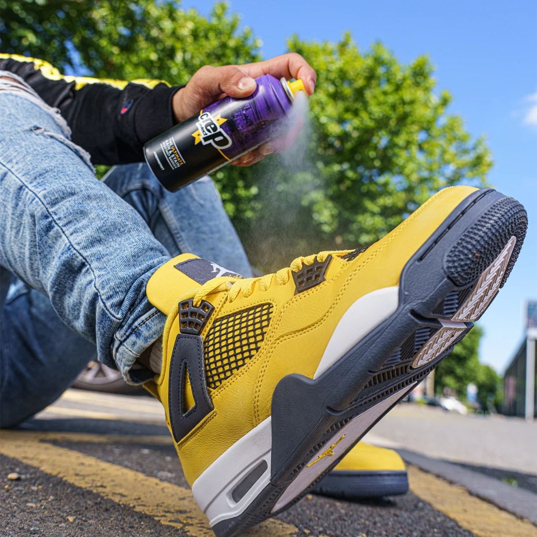 Persona aplicando Crep Protect Spray a sneaker amarilla para protección contra agua y manchas.