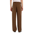 Pantalón Dickies 247 Loose GD en marrón Timber sobre modelo visto de espalda, con las manos en los bolsillos traseros ribeteados y el bolsillo lateral con etiqueta Dickies visible.