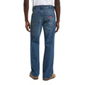 Vista trasera de modelo con vaqueros Dickies 954 Relaxed Straight Work Jeans classic blue, con dos bolsillos de parche, etiqueta roja Dickies, trabillas de cinturón y zapatillas.