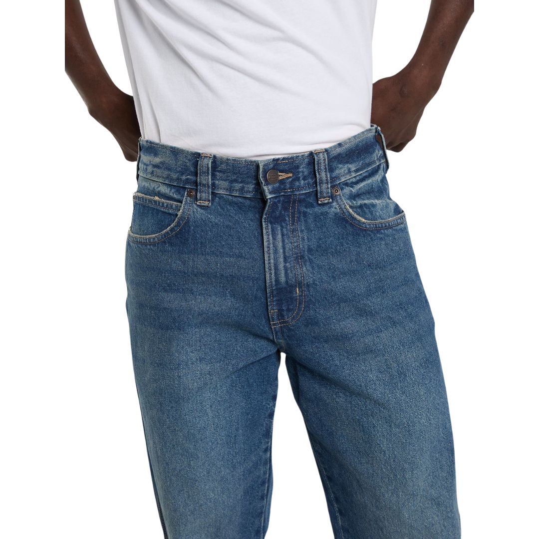 Detalle de la cintura de los vaqueros Dickies 954 Relaxed Straight Work Jeans classic blue sobre modelo, con botón metálico, remaches, trabillas y bolsillo delantero con costuras.