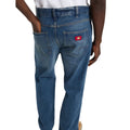 Detalle trasero de modelo con vaqueros Dickies 954 Relaxed Straight Work Jeans classic blue, con la mano en el bolsillo de parche, etiqueta roja Dickies y trabillas de cinturón.
