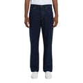 Vista frontal de modelo con vaqueros Dickies 983 Regular Straight Jeans rinsed de pierna recta, con botón metálico, cinco bolsillos, costuras vistas en contraste y zapatillas blancas.
