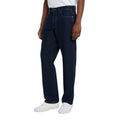 Modelo con vaqueros Dickies 983 Regular Straight Jeans rinsed en vista lateral tres cuartos, con bolsillo delantero, costura lateral simple, pierna recta y zapatillas blancas.