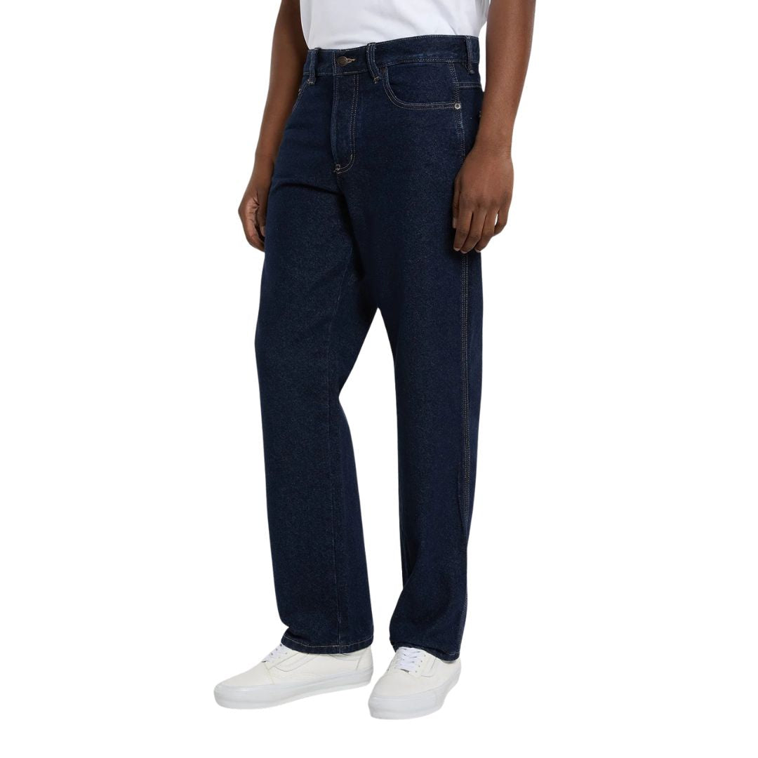 Modelo con vaqueros Dickies 983 Regular Straight Jeans rinsed en vista lateral tres cuartos, con bolsillo delantero, costura lateral simple, pierna recta y zapatillas blancas.