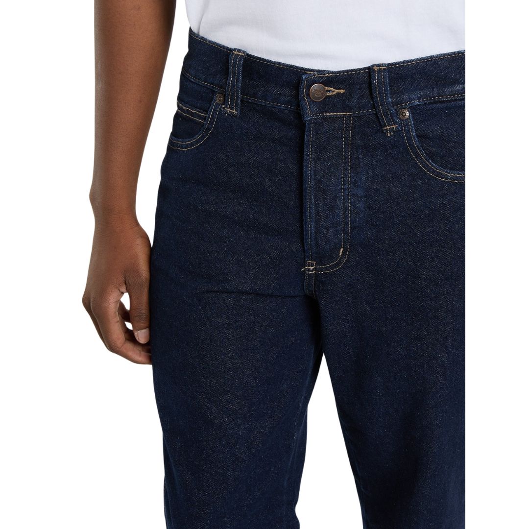 Detalle de la cintura de los vaqueros Dickies 983 Regular Straight Jeans rinsed sobre modelo, con botón metálico, remaches, trabillas de cinturón y bolsillo delantero con costuras.
