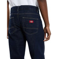 Primer plano del bolsillo trasero en punta con etiqueta roja Dickies de los vaqueros 983 Regular Straight Jeans rinsed, con doble costura en contraste y trabillas de cinturón.