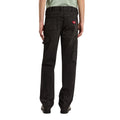 Vista trasera de modelo con vaqueros Dickies 993 Regular Tapered Carpenter black, con etiqueta roja en el bolsillo, trabilla para martillo y bolsillo utilitario en la pierna.
