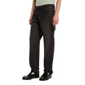 Modelo con vaqueros Dickies 993 Regular Tapered Carpenter black en vista lateral tres cuartos, con trabilla para martillo en el lateral y mocasines negros de charol.