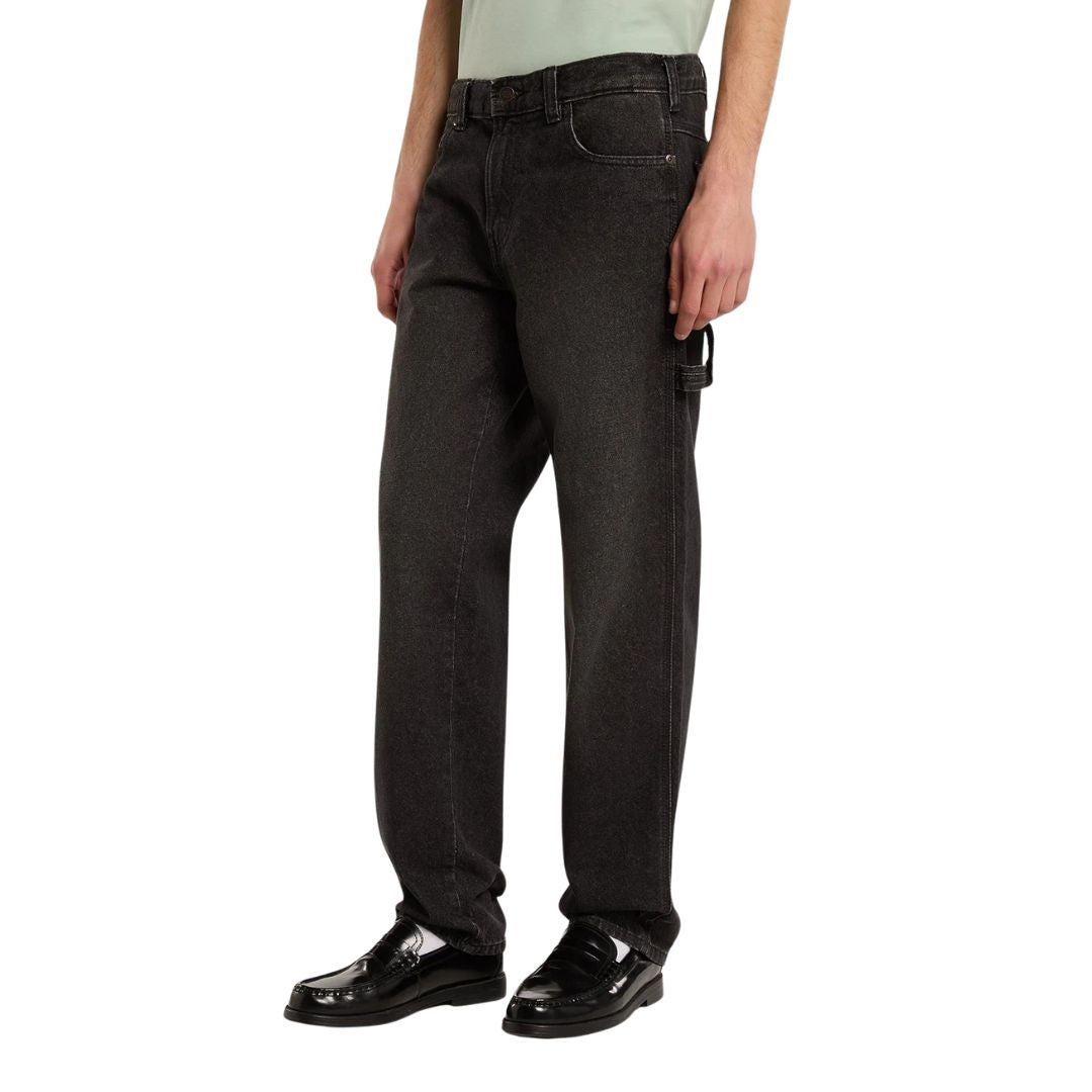 Modelo con vaqueros Dickies 993 Regular Tapered Carpenter black en vista lateral tres cuartos, con trabilla para martillo en el lateral y mocasines negros de charol.