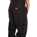Primer plano del bolsillo trasero con etiqueta roja Dickies y del bolsillo utilitario lateral de los vaqueros 993 Regular Tapered Carpenter black, con refuerzos de costura.