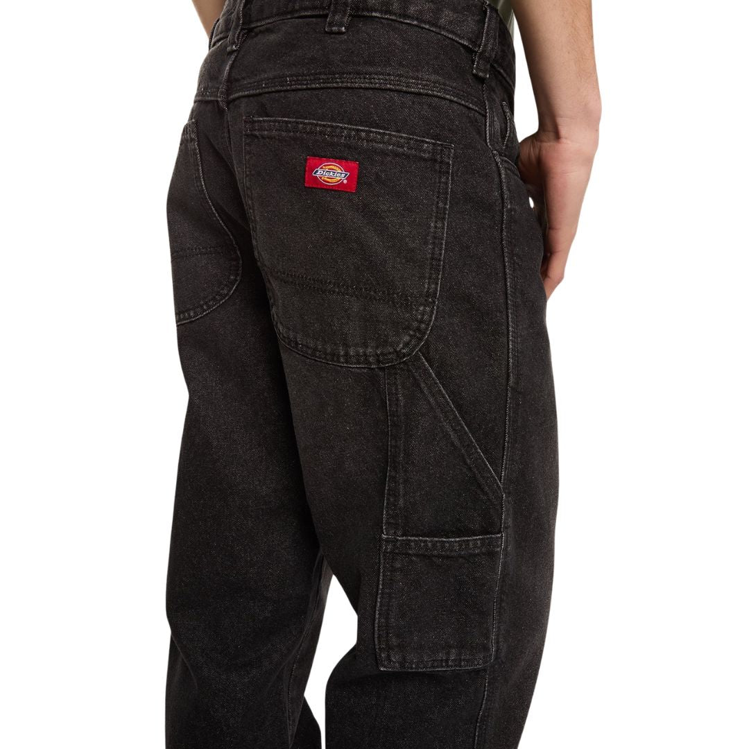Primer plano del bolsillo trasero con etiqueta roja Dickies y del bolsillo utilitario lateral de los vaqueros 993 Regular Tapered Carpenter black, con refuerzos de costura.