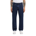Vista frontal de modelo con vaqueros Dickies 993 Regular Tapered Carpenter dark indigo de pierna recta, con botón metálico, cinco bolsillos y zapatillas blancas.