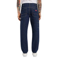 Vista trasera de modelo con vaqueros Dickies 993 Regular Tapered Carpenter dark indigo, con etiqueta roja Dickies, bolsillos de parche y bolsillo utilitario lateral.