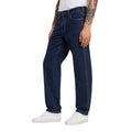 Modelo con vaqueros Dickies 993 Regular Tapered Carpenter dark indigo en vista lateral tres cuartos, con bolsillo delantero, costura lateral y zapatillas blancas.