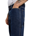 Detalle lateral de los vaqueros Dickies 993 Regular Tapered Carpenter dark indigo con modelo con la mano en el bolsillo delantero y trabilla para martillo en la pierna.