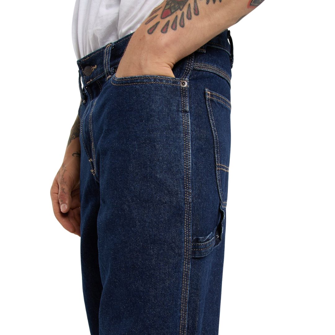 Detalle lateral de los vaqueros Dickies 993 Regular Tapered Carpenter dark indigo con modelo con la mano en el bolsillo delantero y trabilla para martillo en la pierna.