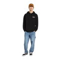 Modelo con sudadera Dickies Donut House Hoodie negra, look urbano con vaqueros y gorro.