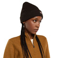 Modelo con el Dickies Gibsland Beanie marrón, gorro de punto con dobladillo vuelto y etiqueta Dickies cosida, sobre un jersey mostaza con cuello alto y cremallera.