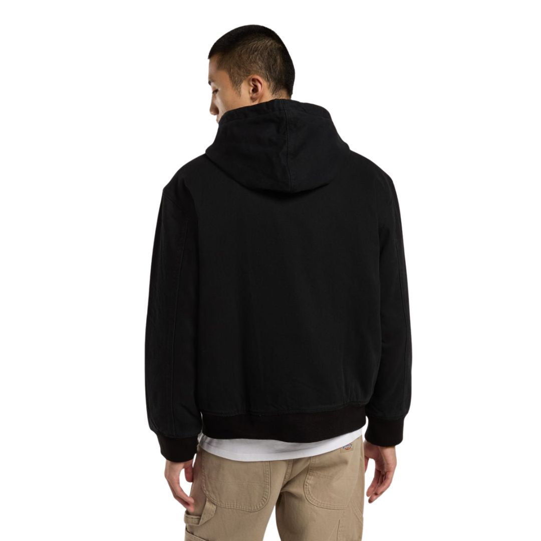 Modelo de espaldas luciendo chaqueta Dickies Hilham Hooded Canvas negra con capucha puesta.