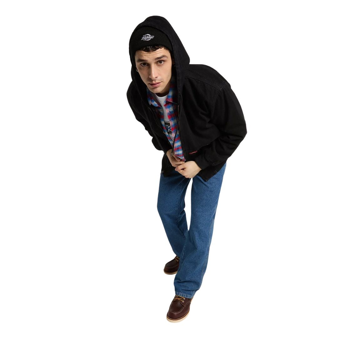Modelo en plano cenital con la Dickies Hilham LN DNM Hood Bomber vaquera negra y capucha puesta, gorro Dickies, camisa de cuadros, vaqueros azules y botas de piel marrones.