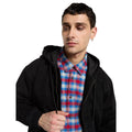 Primer plano de modelo con la Dickies Hilham LN DNM Hood Bomber vaquera negra con la capucha bajada y forro acolchado visible, sobre camisa de cuadros y con cordón en la mano.
