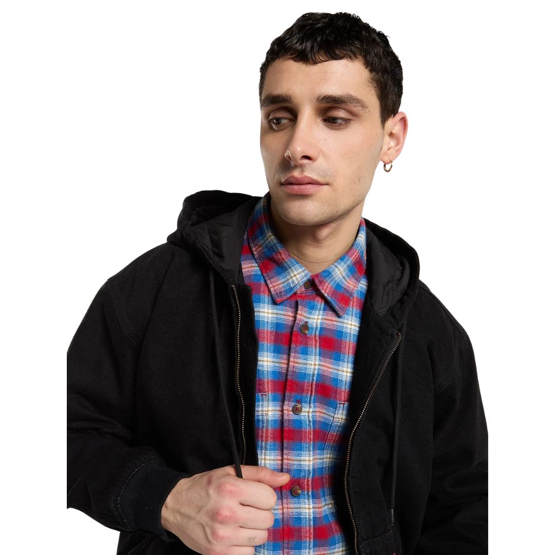 Primer plano de modelo con la Dickies Hilham LN DNM Hood Bomber vaquera negra con la capucha bajada y forro acolchado visible, sobre camisa de cuadros y con cordón en la mano.