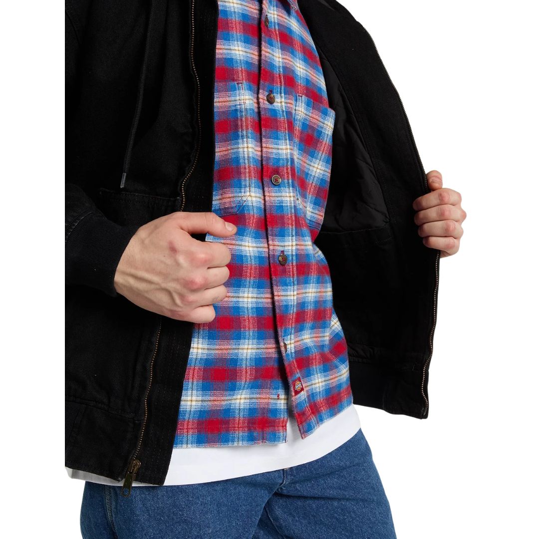 Modelo con la Dickies Hilham LN DNM Hood Bomber negra abierta sobre camisa de cuadros, mostrando el forro acolchado de rombos, el bolsillo canguro y la cremallera metálica.