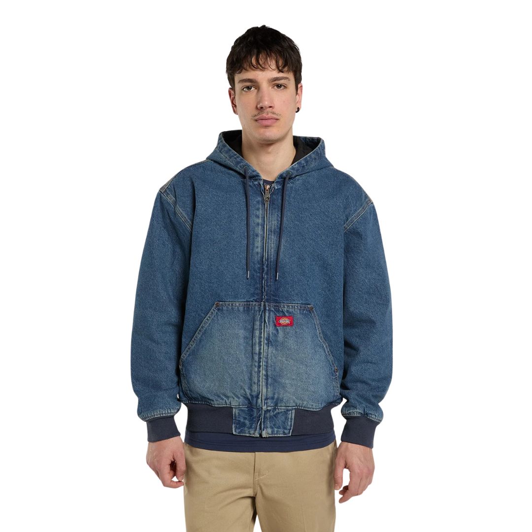 Modelo de frente con la Dickies Hilham LN DNM Hood Bomber vaquera azul lavado y capucha bajada, cordones colgando, bolsillo canguro con etiqueta Dickies y puños acanalados.