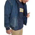 Modelo con la Dickies Hilham LN DNM Hood Bomber vaquera azul lavado abierta, mostrando el forro acolchado de rombos, bolsillo canguro con remaches y camiseta Dickies azul marino.