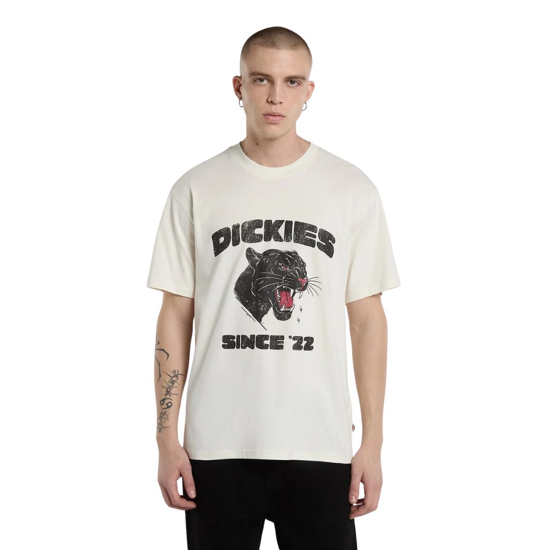 Modelo de frente con la Dickies McDermitt SS Tee blanca crudo, mostrando el estampado gráfico de pantera rugiendo en el pecho y el cuello acanalado.