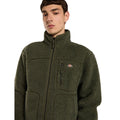 Primer plano de modelo con la Dickies Mount Hope Fleece verde oliva, cuello alto, cremallera cerrada y bolsillo de pecho con cremallera y etiqueta tejida de Dickies.