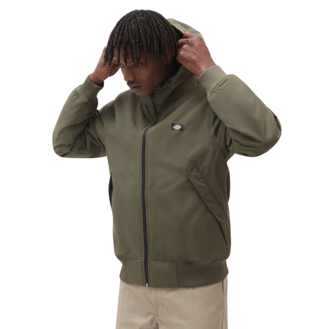 Modelo ajustando la capucha de la chaqueta Dickies New Sarpy verde militar, tejido resistente al agua.