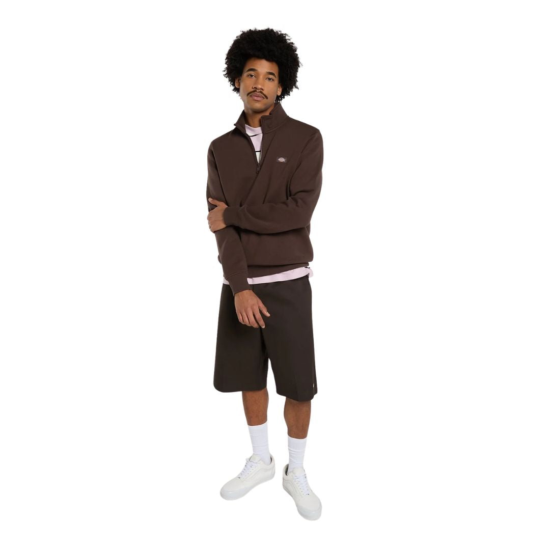 Look completo de cuerpo entero con la sudadera Dickies Oakport Quarter Zip marrón chocolate, bermudas marrón oscuro, calcetines blancos y zapatillas blancas sobre fondo blanco.