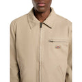 Detalle frontal de la chaqueta Dickies Painter Jacket Canvas color desert sand con logo Dickies y bolsillo con cremallera.