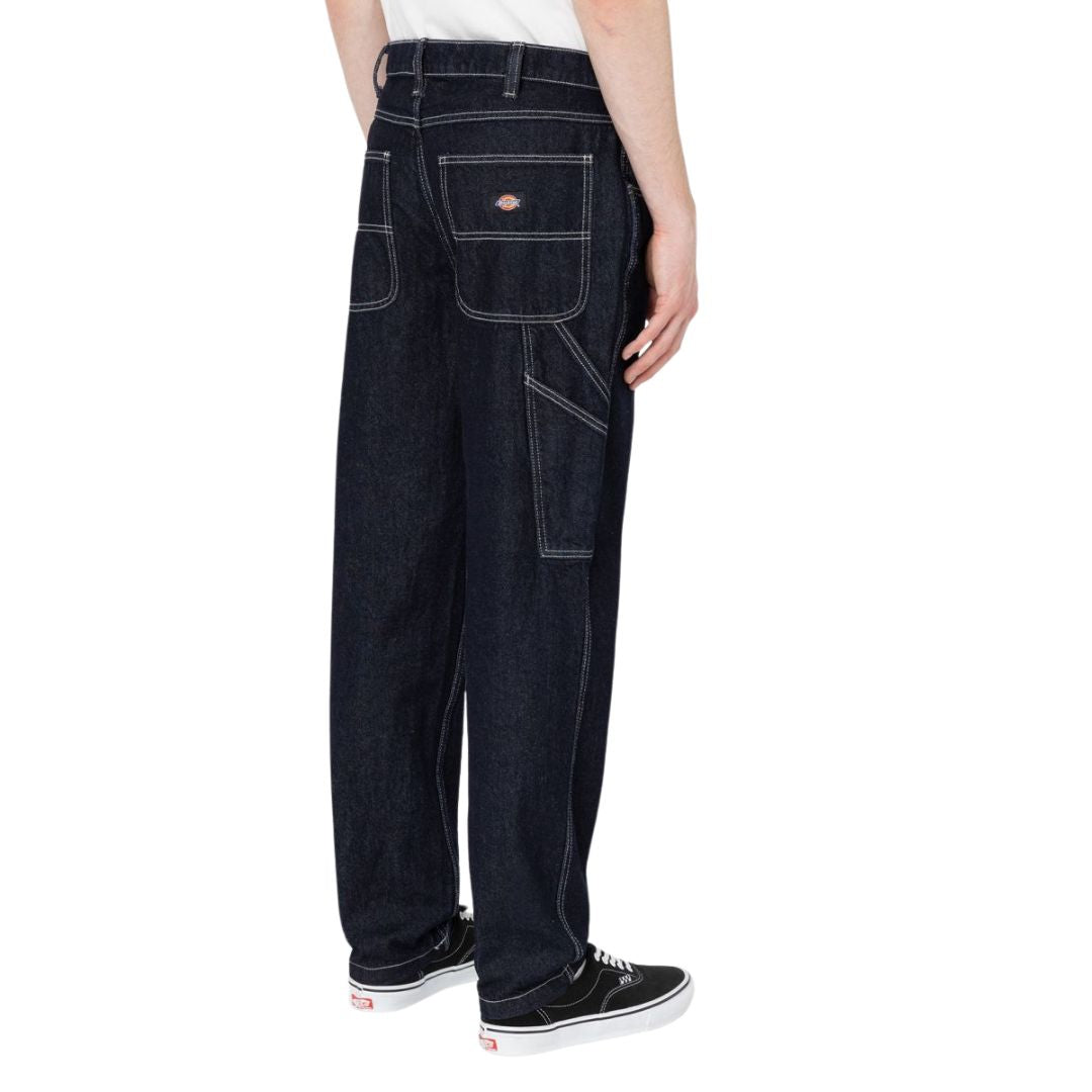 Vista lateral en modelo con el pantalón Dickies Garyville Denim indigo oscuro rinsed.