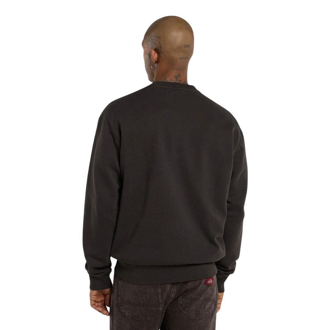 Modelo de espaldas con la Dickies Sutcliffe Sweatshirt, sudadera de cuello redondo marrón oscuro de corte relaxed, sobre un pantalón vaquero marrón oscuro.
