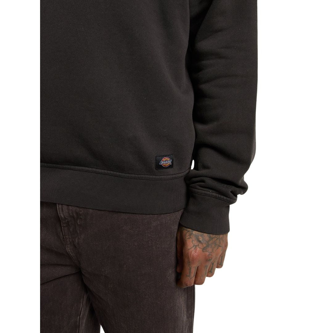 Detalle del bajo y el puño acanalados de la Dickies Sutcliffe Sweatshirt marrón oscuro, con la etiqueta Dickies cosida, sobre un pantalón marrón oscuro.