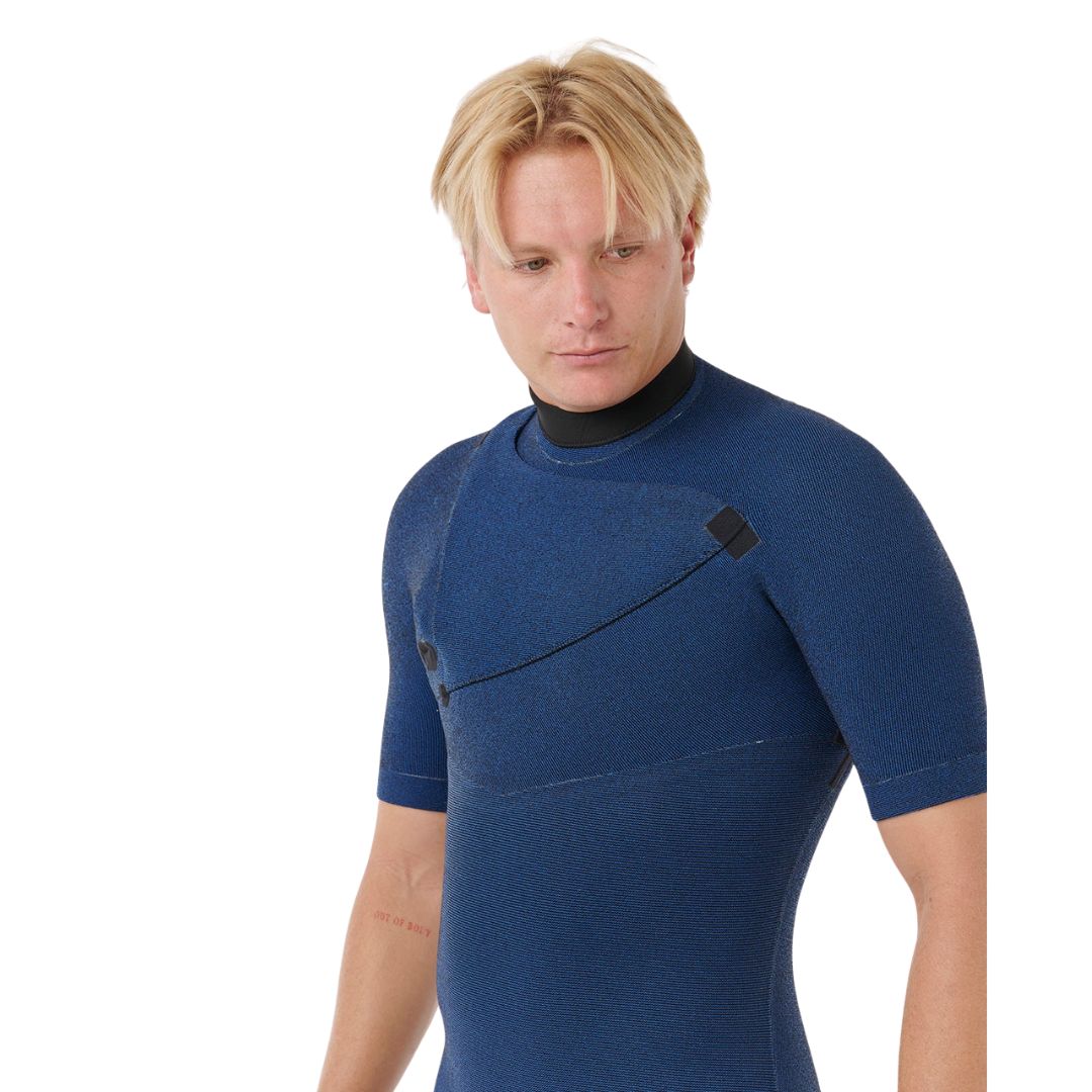 Detalle del pecho y hombro del traje Rip Curl E-Bomb 2/2 azul marino jaspeado, con costuras selladas GB Seam, sistema de apertura sin cremallera y cuello negro de neopreno.