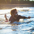Hombre surfista con protector solar blanco en la cara usando stick solar SPF50+ bio resistente al agua en el mar.