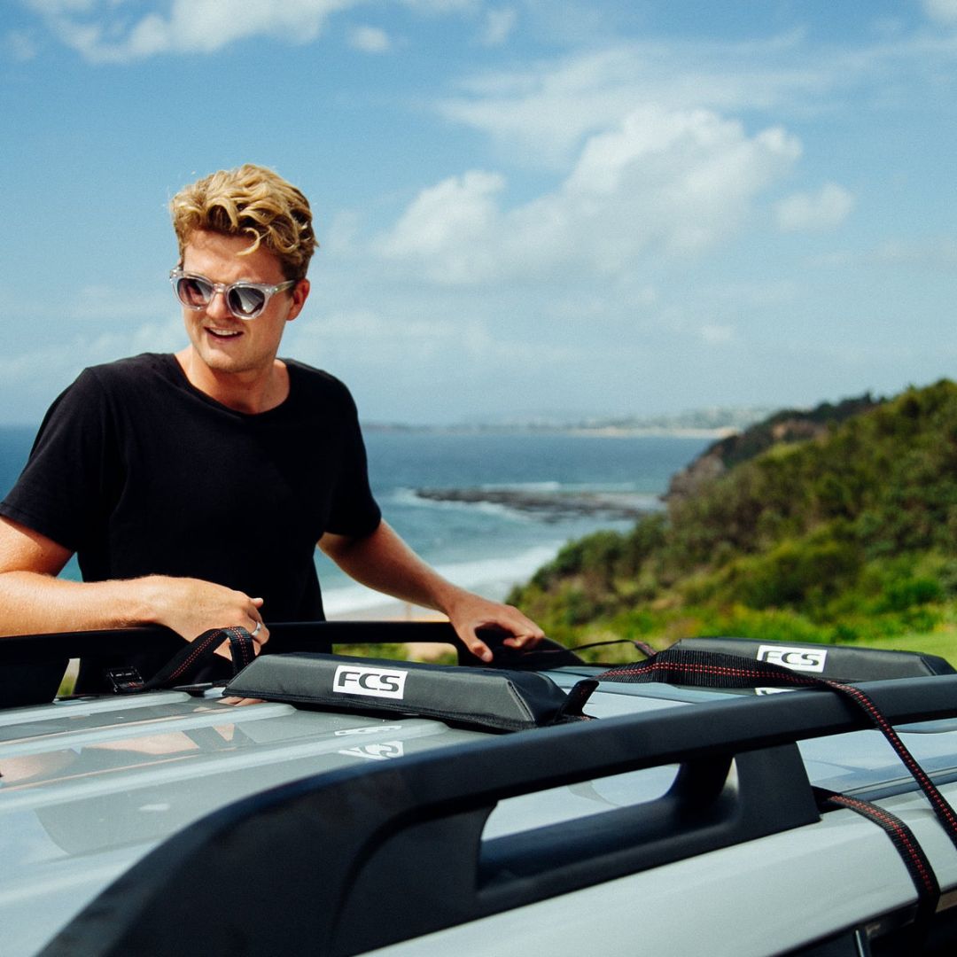 FCS Cam Lock Soft Racks Single instalados en el techo de un coche transportando tablas de surf sin baca.