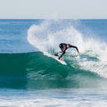 Surfista realizando un giro pronunciado con gran proyección de agua en una ola, imagen de contexto de surf asociada al set de quillas Firewire Velox.