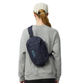 Fjällräven Skule Sling 6 azul marino llevada cruzada en la espalda, bandolera urbana 6L con cordón elástico frontal y ajuste cómodo.