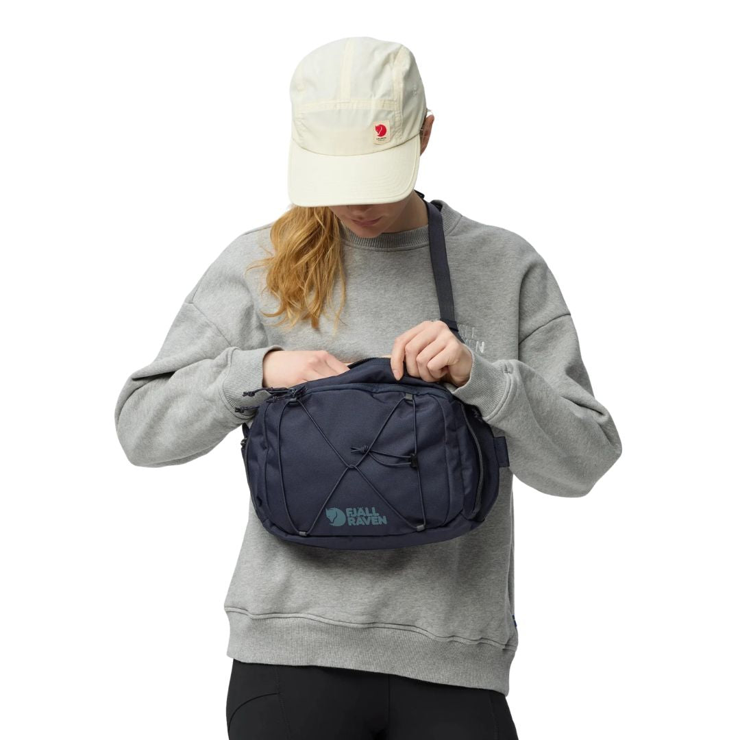 Detalle bolsillo frontal con cremallera y gancho para llaves en Fjällräven Skule Sling 6 azul marino.