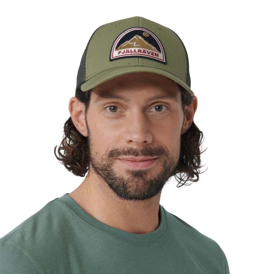 Hombre con gorra Fjällräven Badge Långtradarkeps vista frontal mostrando diseño trucker con parche bordado y ajuste regulable.