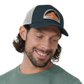 Hombre con gorra Fjällräven Badge Långtradarkeps vista lateral destacando parche frontal y paneles de malla.