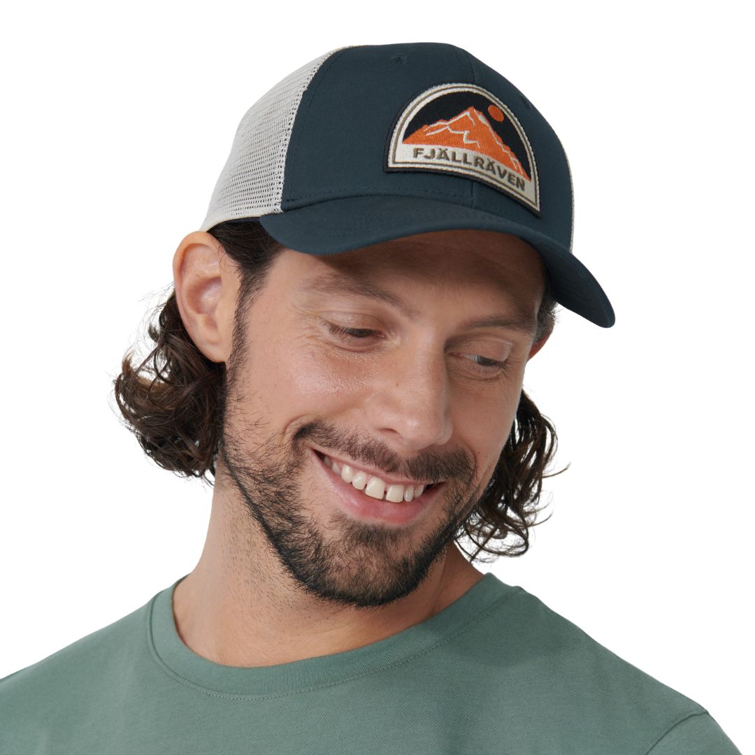 Hombre con gorra Fjällräven Badge Långtradarkeps vista lateral destacando parche frontal y paneles de malla.