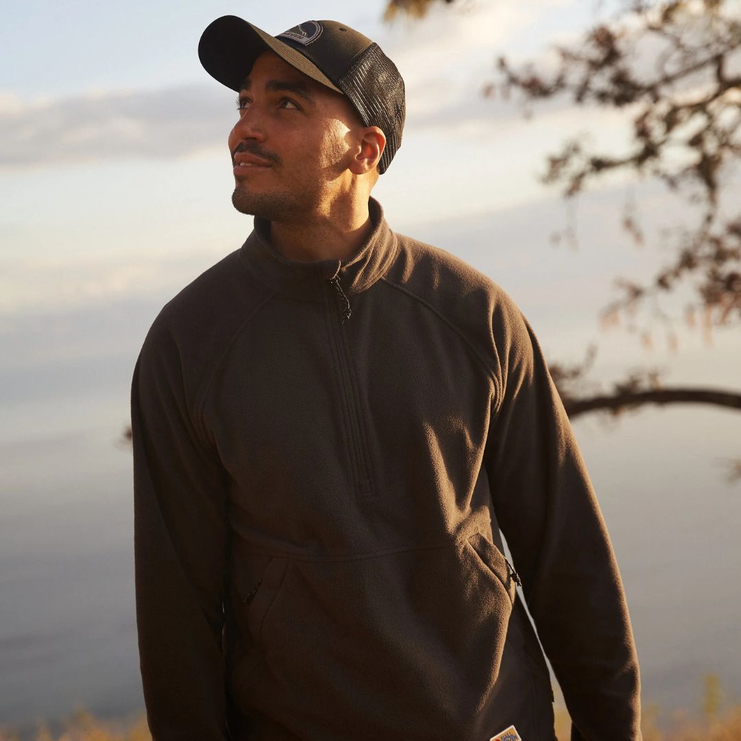 Hombre con gorra Fjällräven Badge Långtradarkeps en entorno natural destacando diseño transpirable y ajuste cómodo.